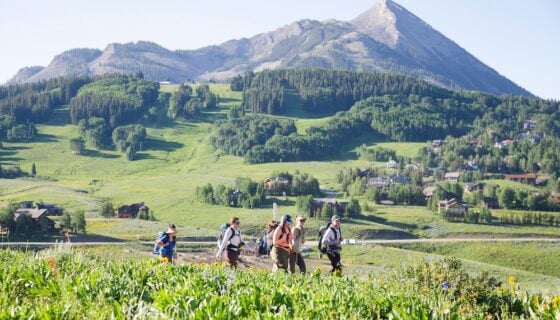 MS Ecology students hike up Snodgrass carrying backpacks and equipment with Mt. Crested Butte in the background.