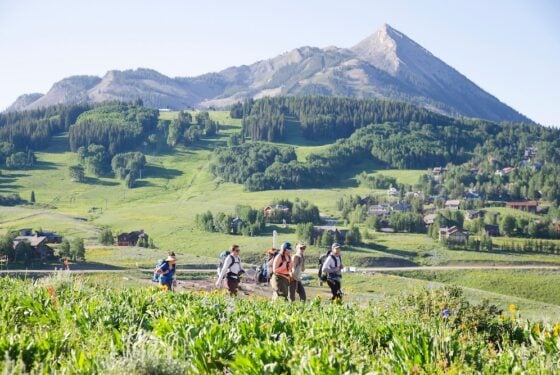 MS Ecology students hike up Snodgrass carrying backpacks and equipment with Mt. Crested Butte in the background.