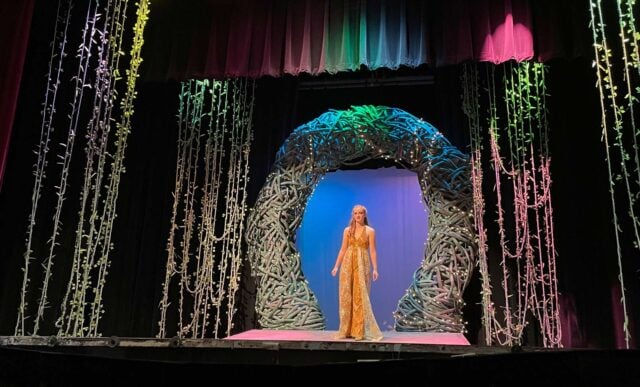 An actress stands on a beautifully designed stage.