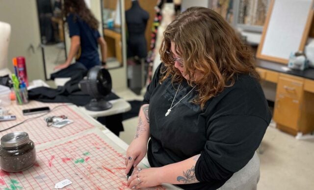 A student cuts something in preparation for a play.