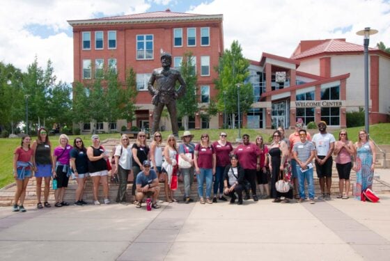 A photo of a tour group in front of the Mountaineer Statue.