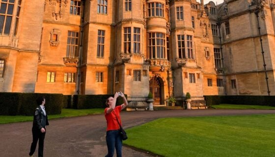 Two students walk outside of the Harlaxton Manor at sunset.