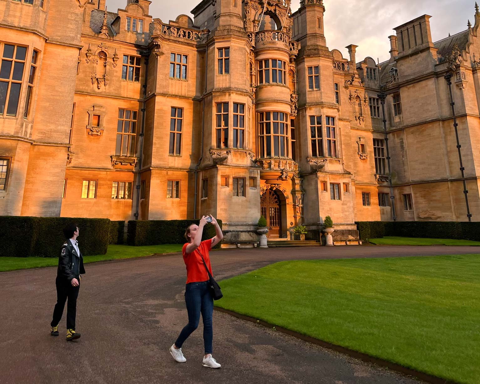 Two students walk outside of the Harlaxton Manor at sunset.