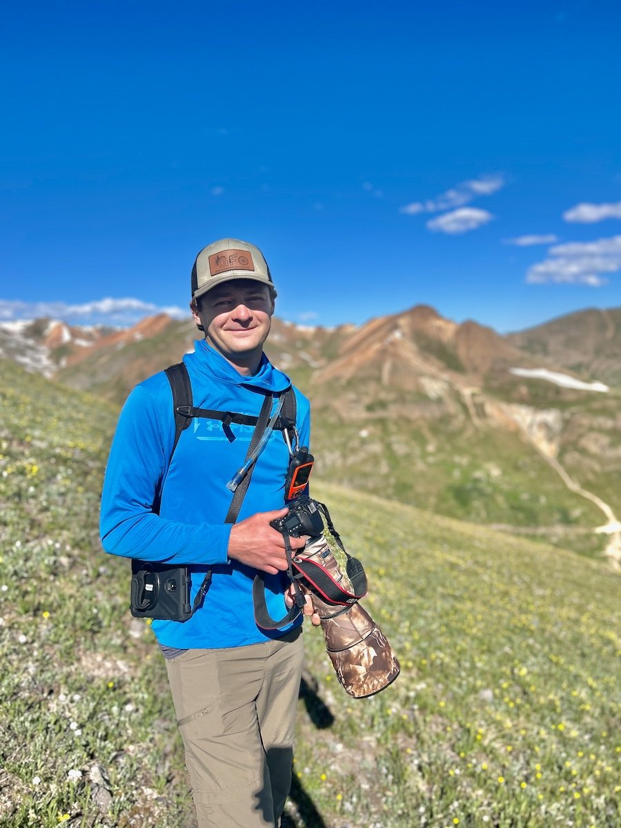 Arrow Meyers holds his scope on a grassy hill.