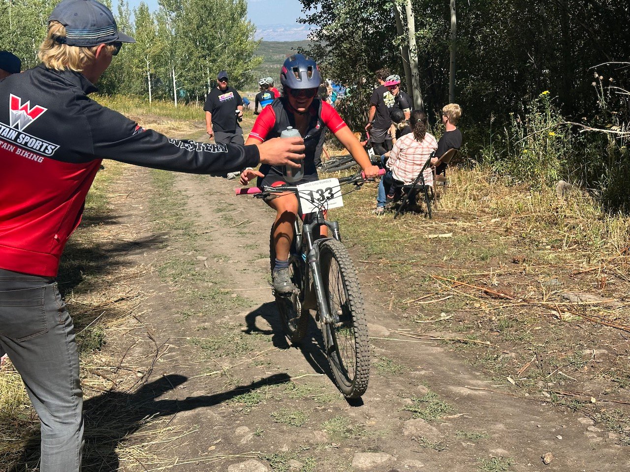 Western Mountain Bike teammate collects water at a race.