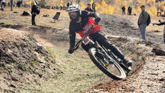 A Western Athlete competes in the Dual Slalom at Nationals with a blue sky and golden aspens in the background.