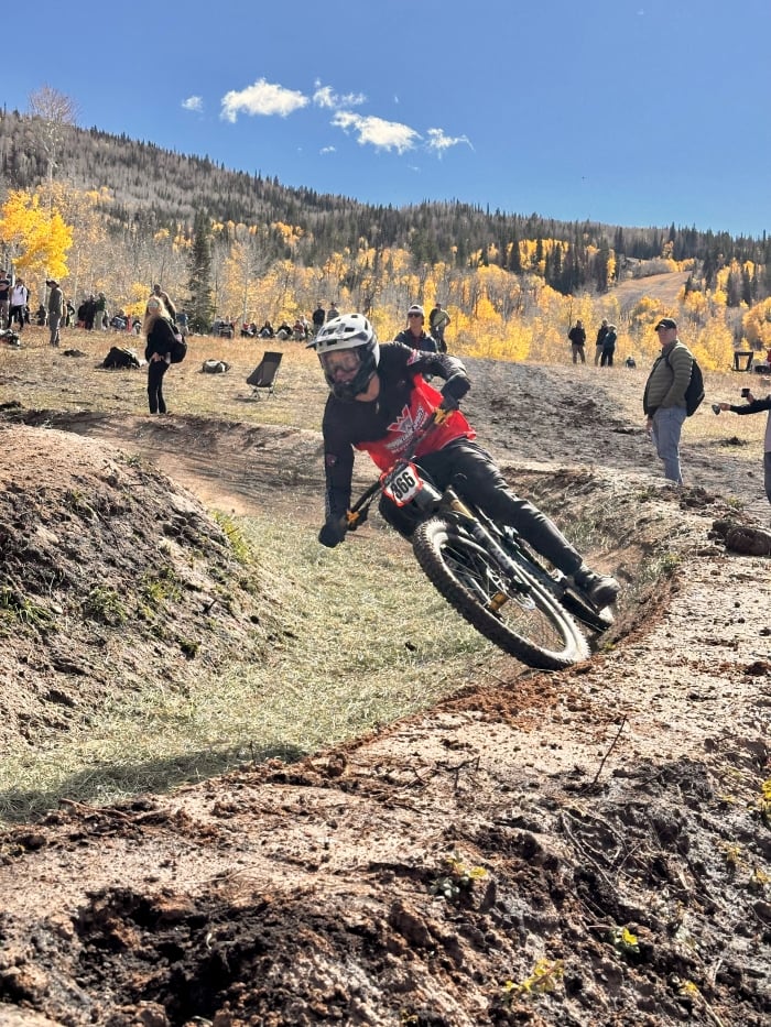 A Western Athlete competes in the Dual Slalom at Nationals with a blue sky and golden aspens in the background.