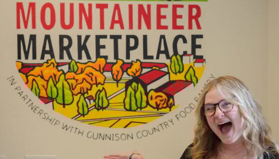 Abbie Showman - artist of Mountaineer Marketplace Mural stands in front of her work