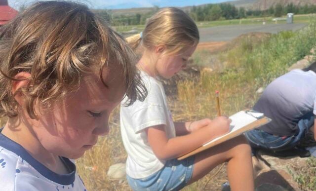Junior Mountaineer Campers take notes while on an outdoor adventure.
