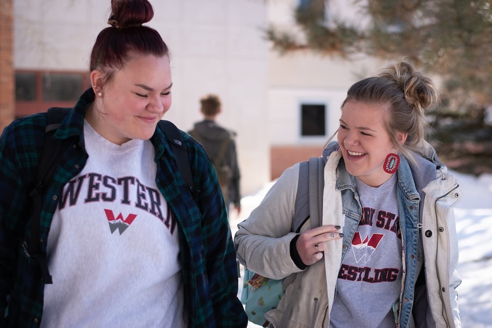 Two female students laugh together.