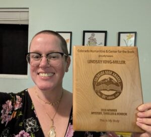 Lindsay King-Miller smiles while holding up her Colorado Book Award plaque.