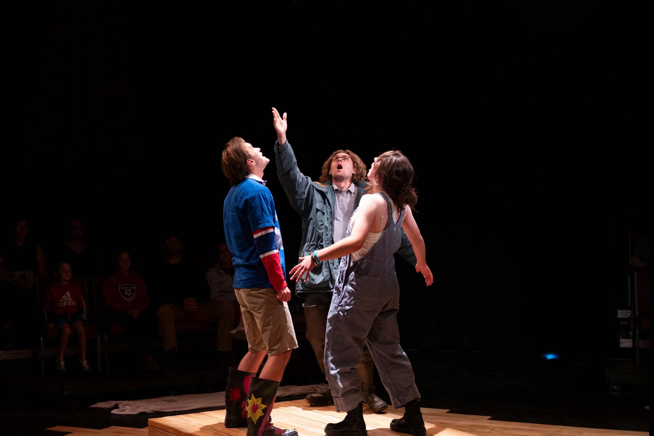 Three students standing on stage during a play.