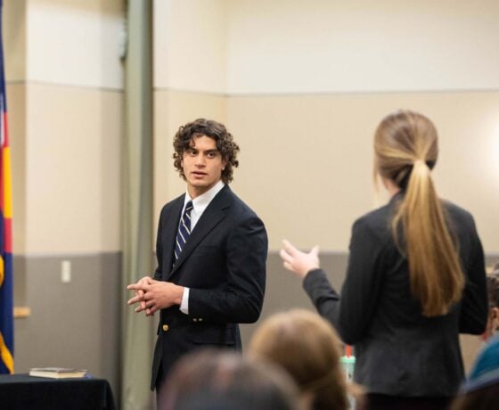 Three students acting as the defense team take notes during a mock trial scrimmage against CMU.