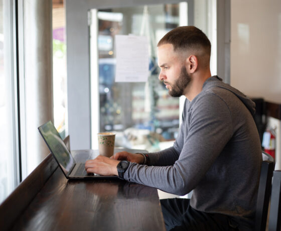 John Gonzales types on a laptop at Tributary Coffee for the ADC Photoshoot.