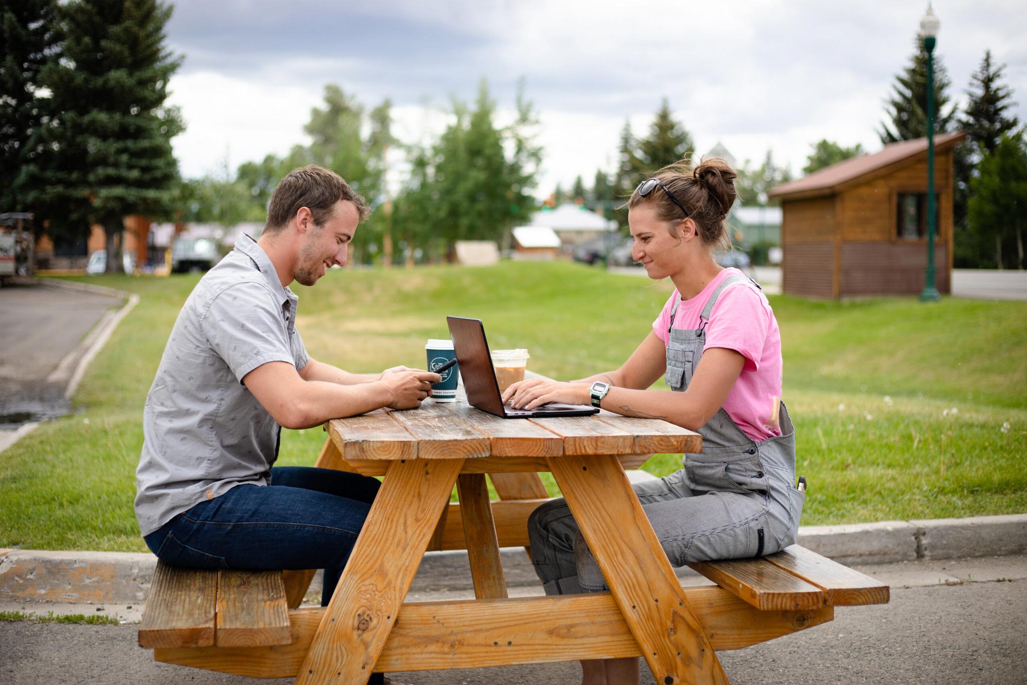 Eliza Lockhard types on a laptop while sitting at a picnic table outside of Mochas.