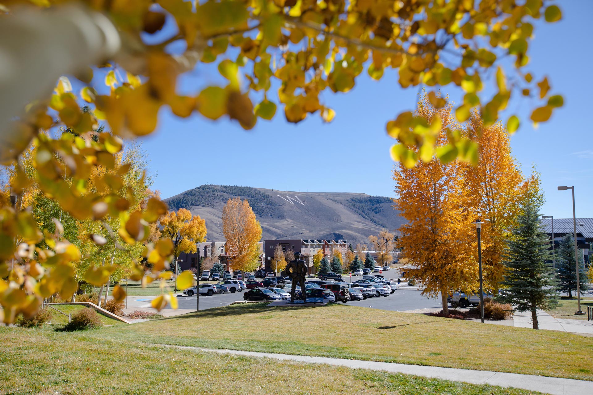 A photo of W Mountain taken near the Welcome Center with an aspen branch full of yellow leaves hanging in the top of the fram.