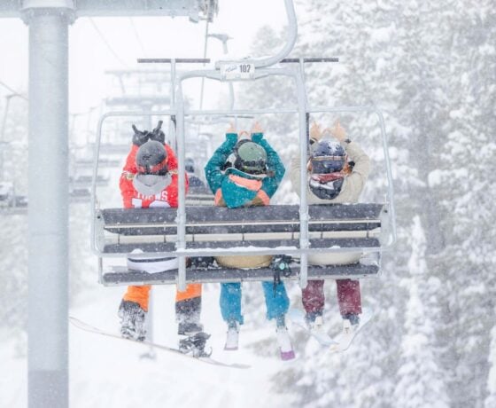 Western Students holding up Ws on a chair lift at Crested Butte mountain.