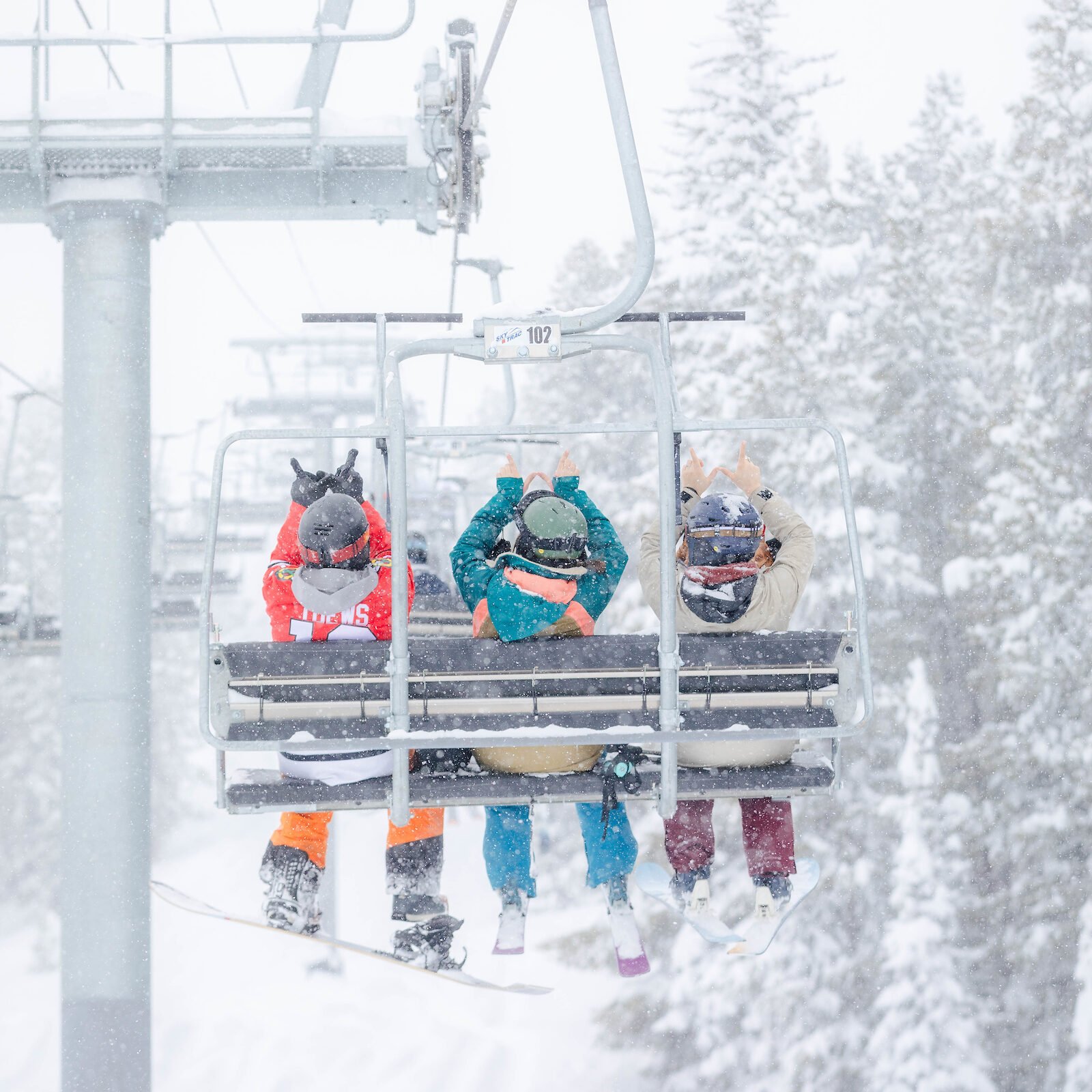 Western Students holding up Ws on a chair lift at Crested Butte mountain.