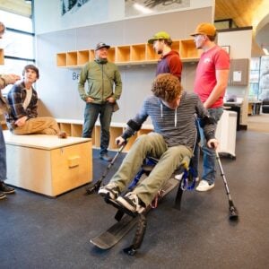 An ROE student tests out a sit ski at the Adaptive Sports Center while a few of his classmates observe.