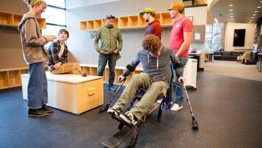 An ROE student tests out a sit ski at the Adaptive Sports Center while a few of his classmates observe.
