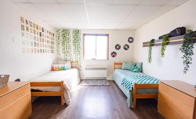 A dorm room with two beds and two dressers inside Ute Hall.