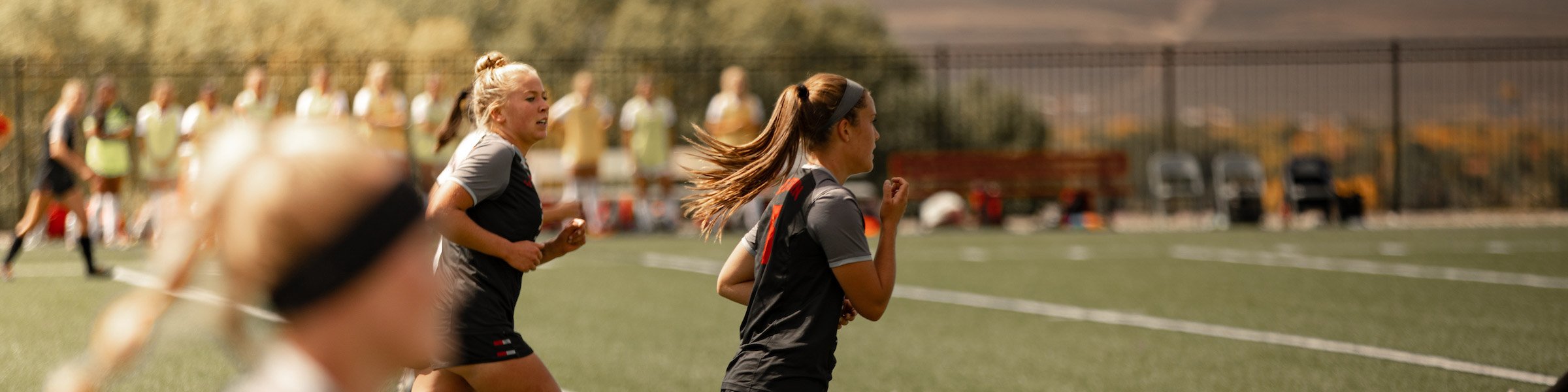 Western soccer players run down the field. Three of them.