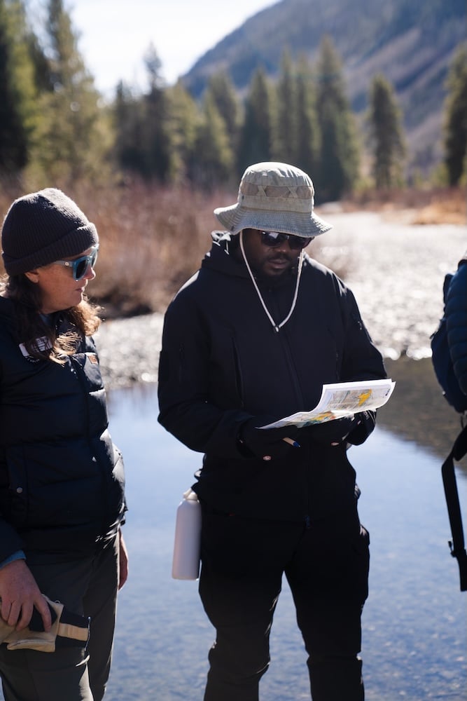 MEM director Dominque Naccarto and MEM student Franklin view the Crested Butte Land Trust property map while standing next to the Slate River.