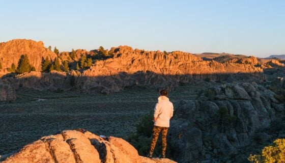 A student stands on a rock formation at Hartman Rocks during golden hour.