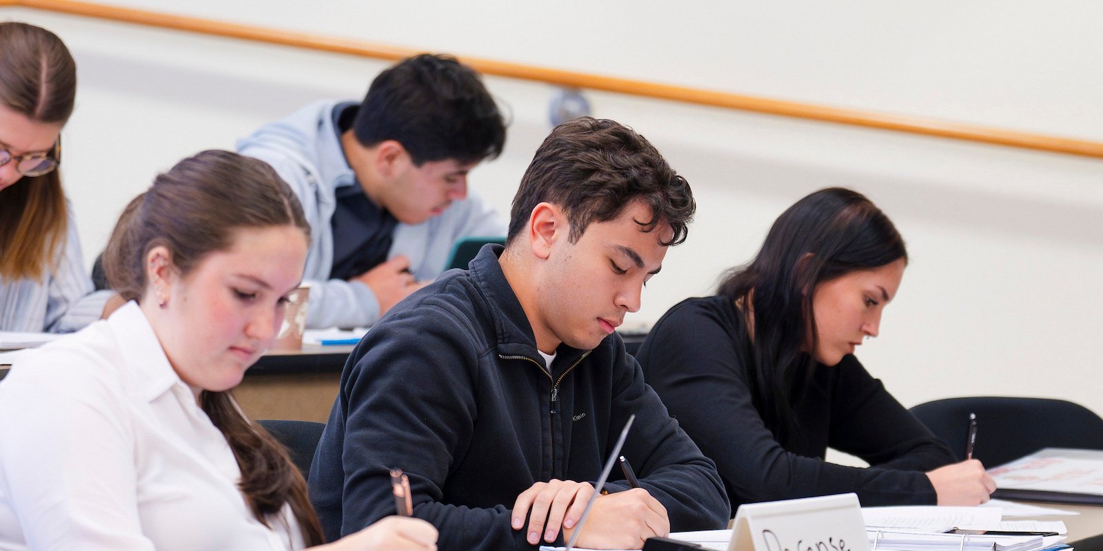 Three students acting as the defense team take notes during a mock trial scrimmage against CMU.