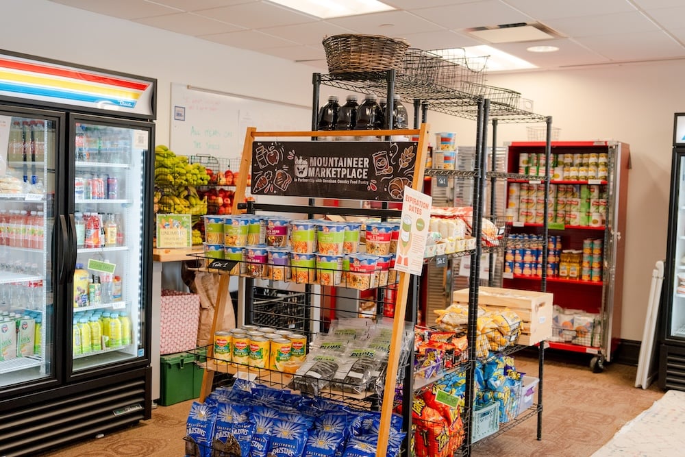 The interior of the Mountaineer Marketplace with a fridge, cabinets, and shelves full of food.