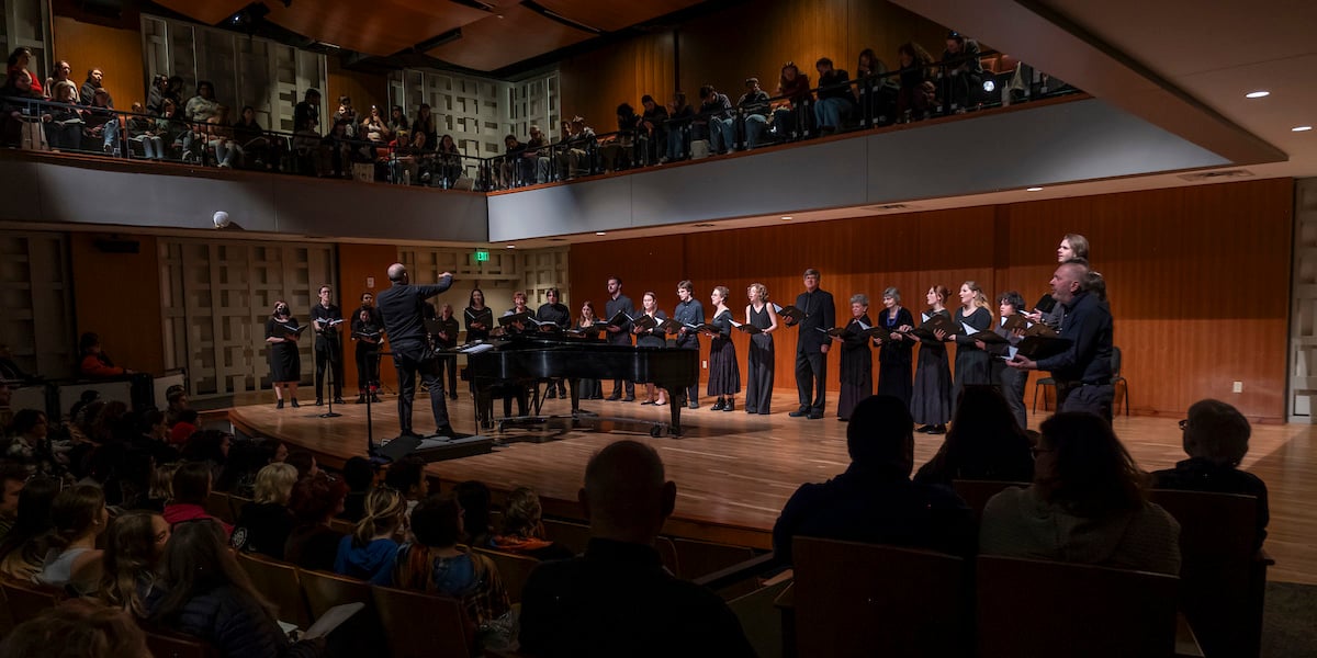 A wide shot looking at the stage from the back of Kincaid Concert hall of the Western Choir performing for the community.