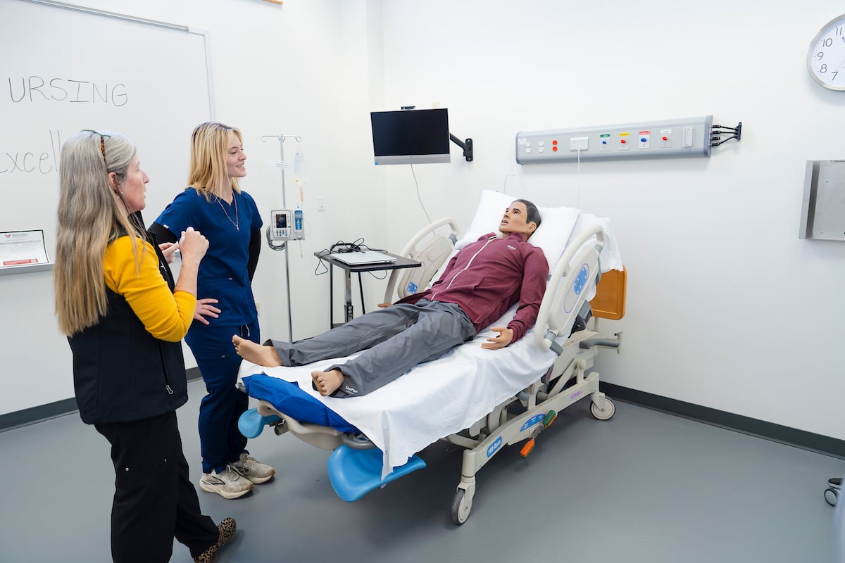 Nursing faculty, Mary Sawyer, shows the mannequin 'Sim Man' to one of her students in the Simulation Lab.