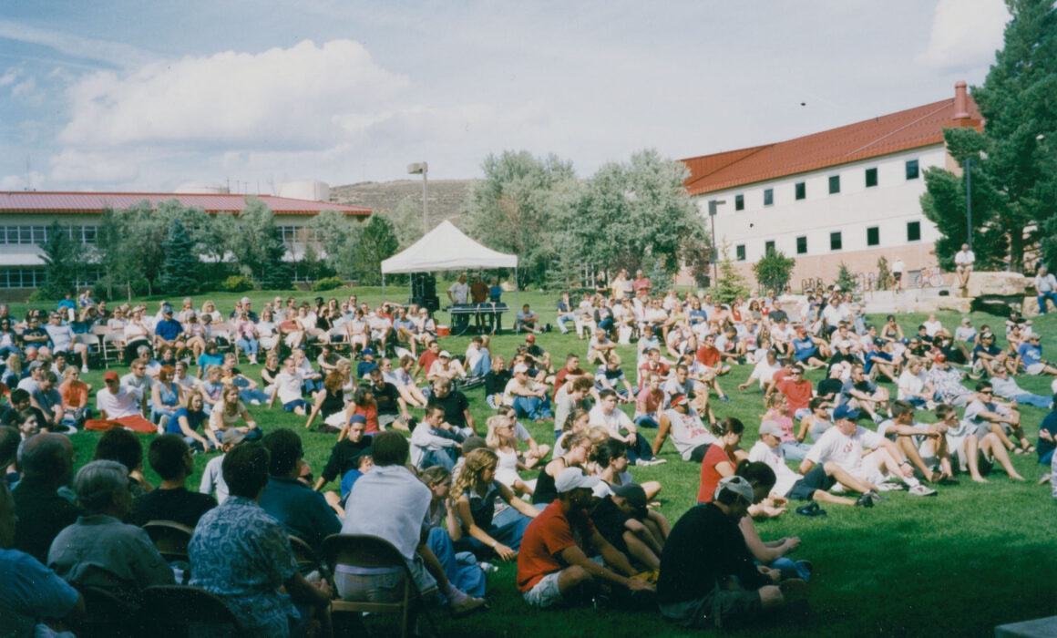 A Freshman Convocation takes place at Quigley Bandshell, 2002. Kelley and Hurst Halls are in the background.