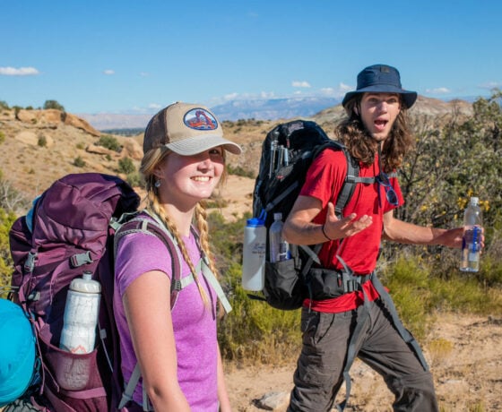 Two students smile while backpacking in the desert.