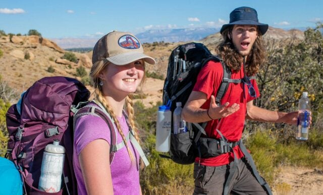 Two students smile while backpacking in the desert.