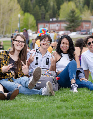 A photo of a group of friends sitting on the lawn at the CB Center for the Arts during the Pride Picnic.