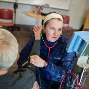 A student takes the blood pressure of a community member.
