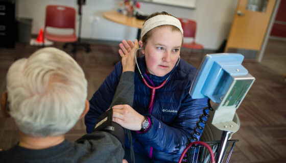 A female student tests the blood pressure of a person.