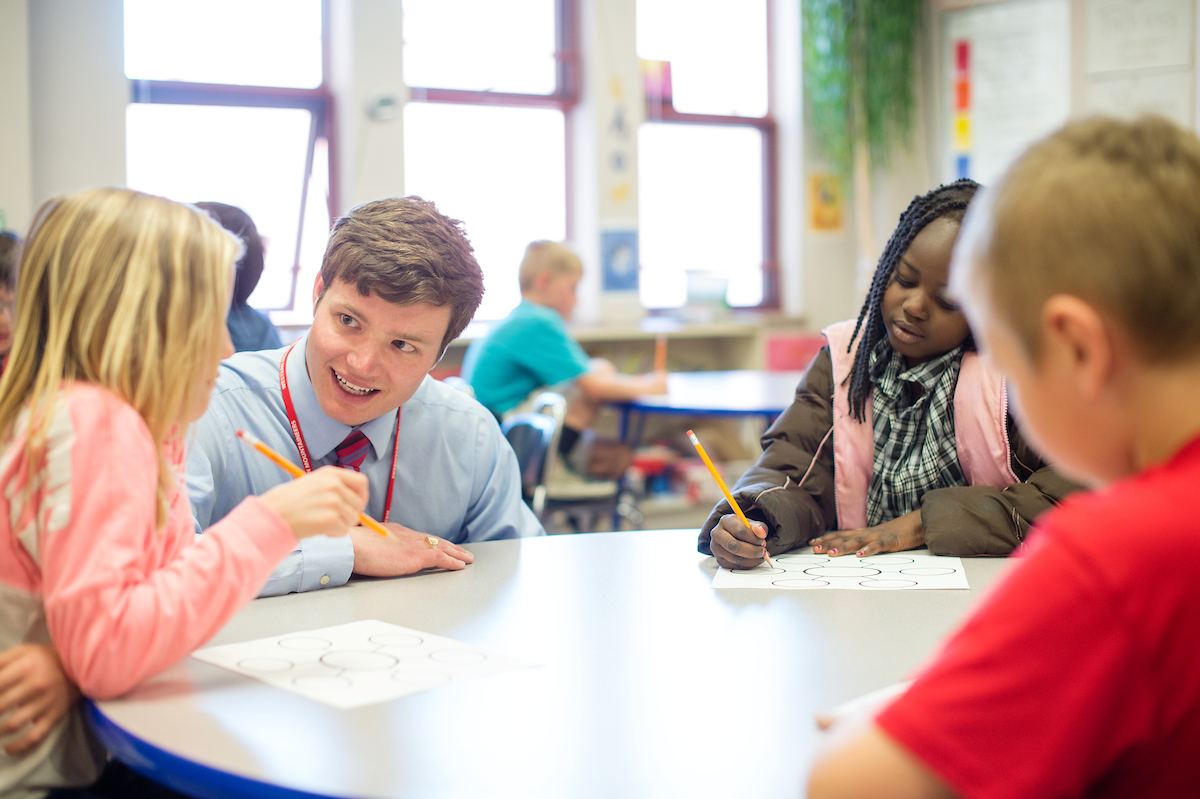 Male student helps students in elementary classes.