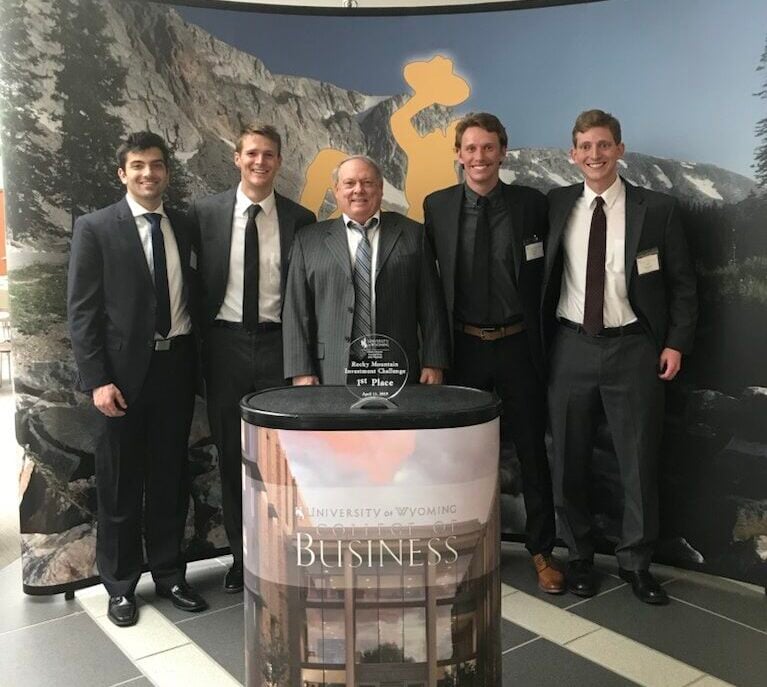 A group of business students take a group photo together in suits.