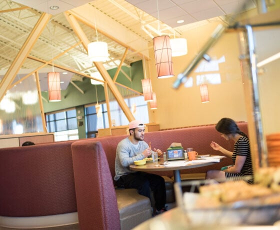 Two students are seated at a booth inside the Rare Air Cafe and eat breakfast.