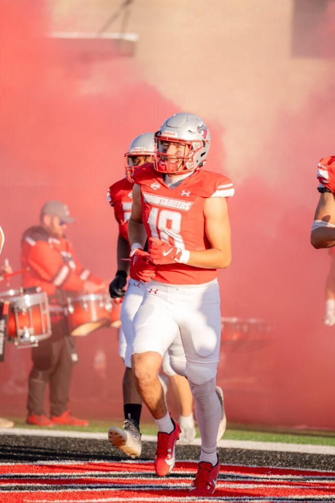 Western player #18 runs onto the field at their pre-game entrance with a smile on his face