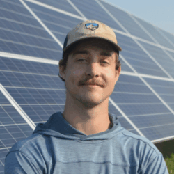 Headshot of Austin Kinzer in front of solar panels.
