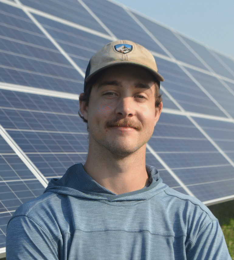 Headshot of Austin Kinzer in front of solar panels.