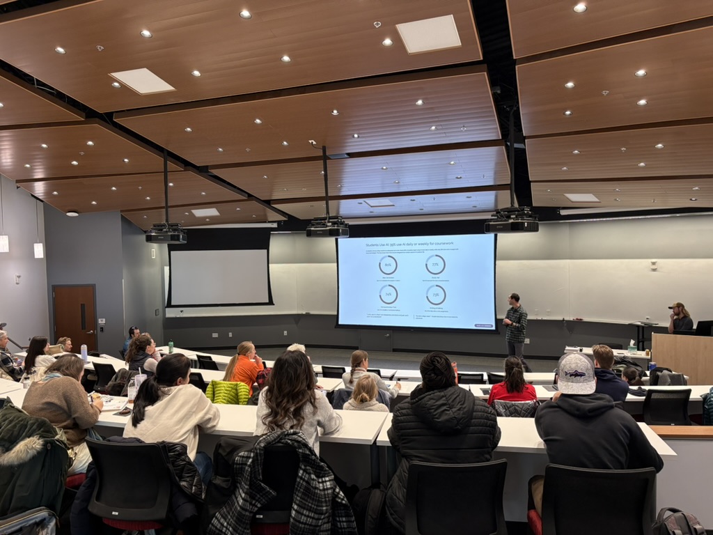 Adults view a presentation inside an auditorium classroom.