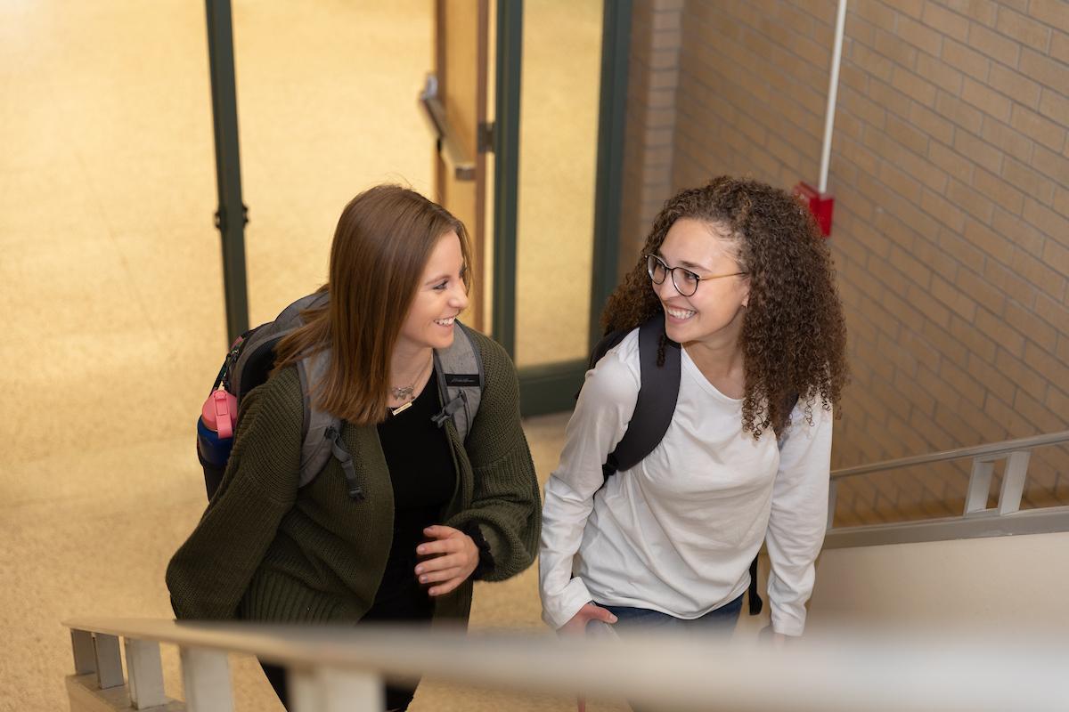 Two students ascend the stairs at the library