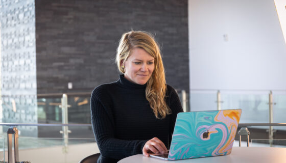 A woman smiles while studying with a laptop.