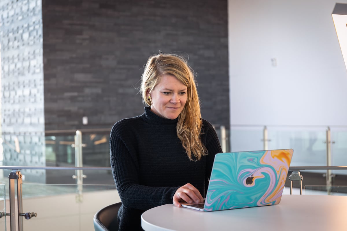 A woman smiles while studying with a laptop.