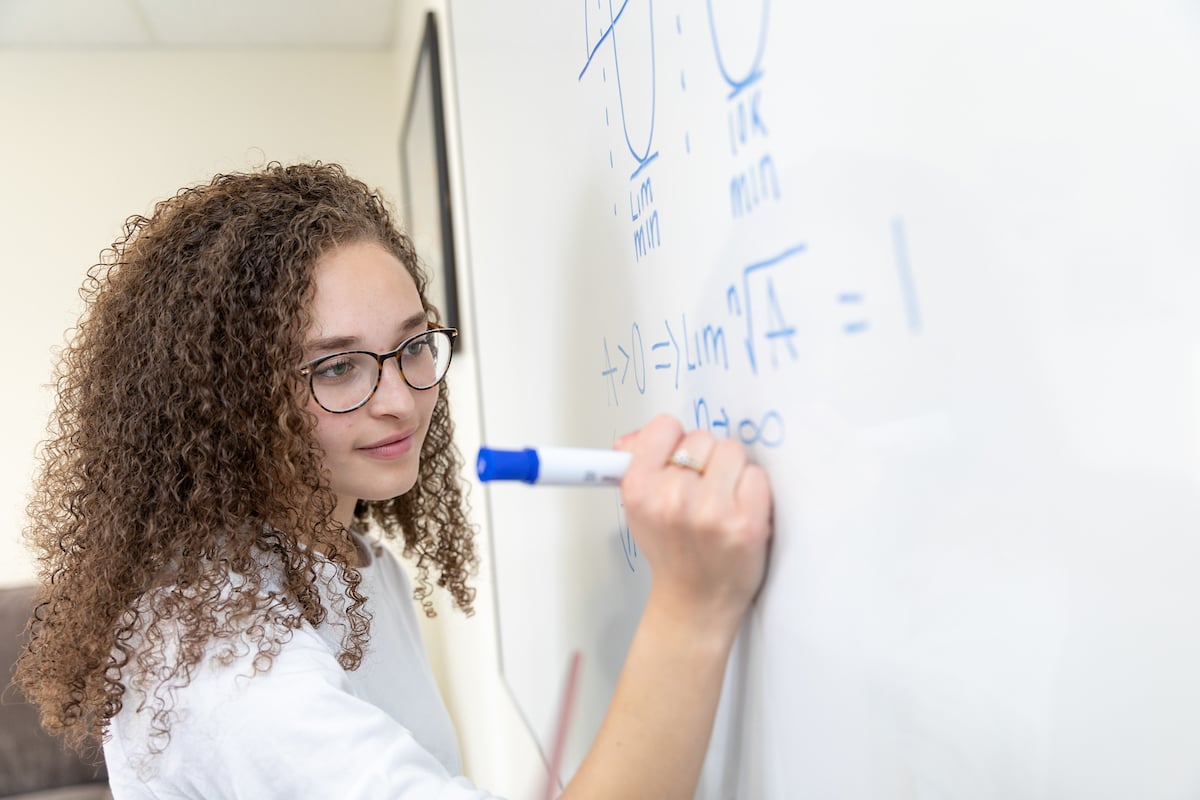 A student writes on a whiteboard.
