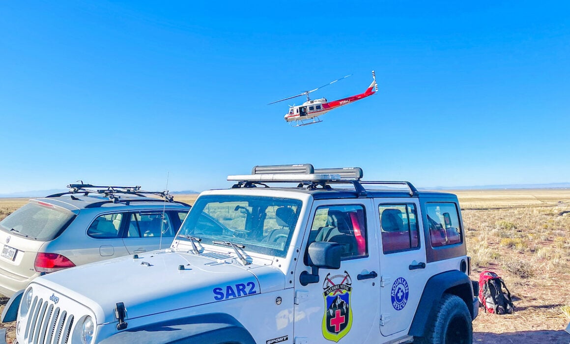 A view of the Mountain Rescue vehicle in 2021 and a partner helicopter in the sky.